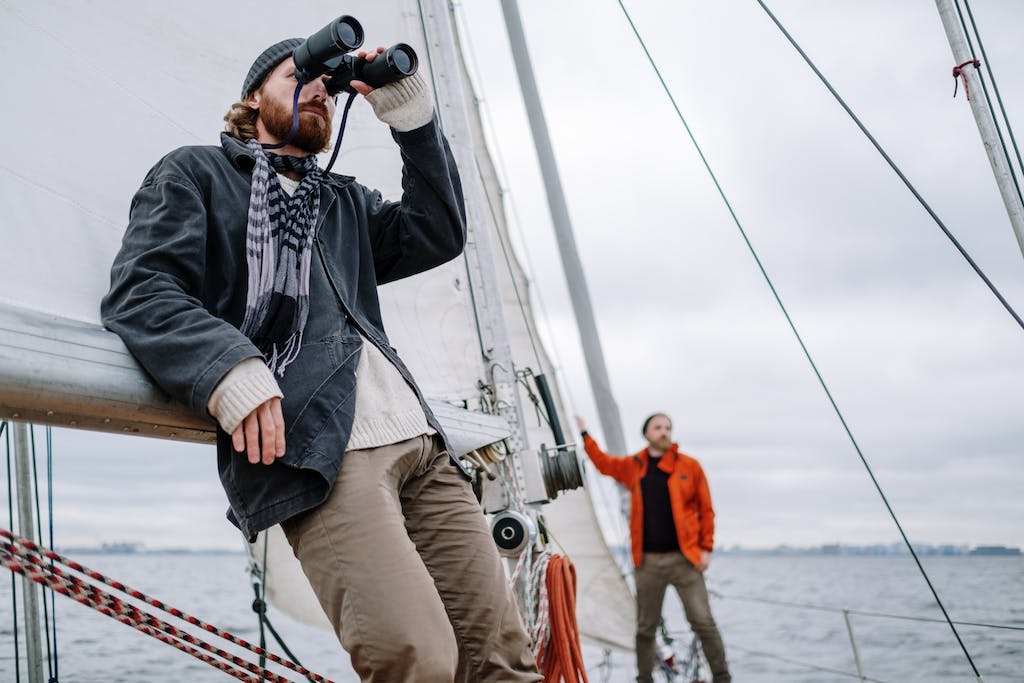 Sailor Looking Around Through Binoculars from the Deck of a Sailboat